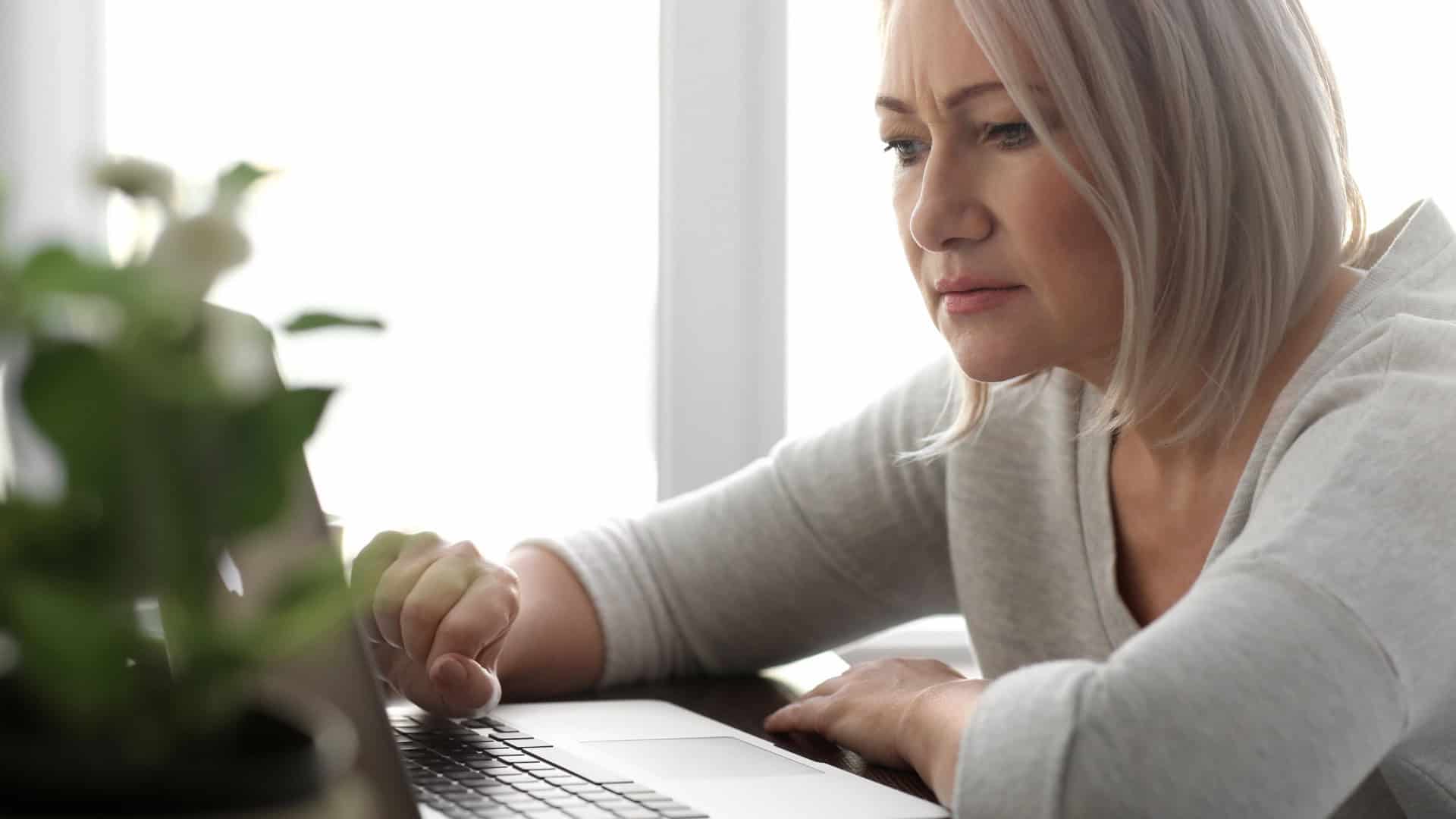 Mulher lendo notícias na tela do laptop