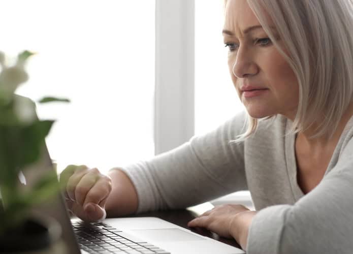 Mulher lendo notícias na tela do laptop