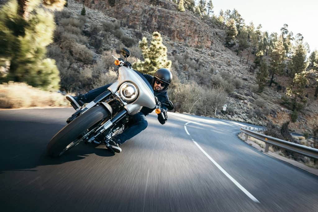 Imagem de um homem pilotando moto em uma curva na estrada
