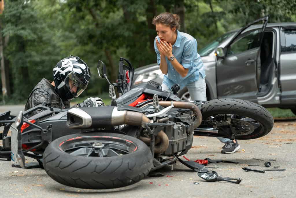 Imagem mostra colisão entre motocicleta e carro na estrada, situação que a garantia de moto não cobre