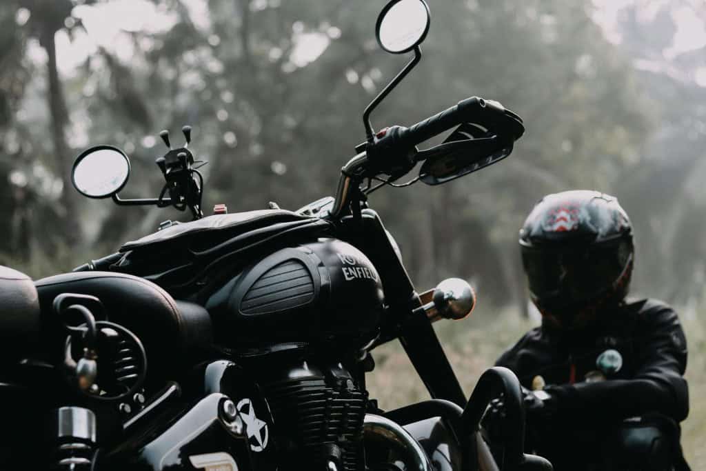 Foto de motocicleta e motociclista sentado pelo caminho