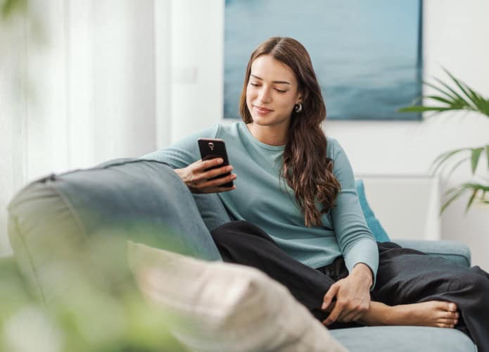 Mulher jovem usando o celular no sofá