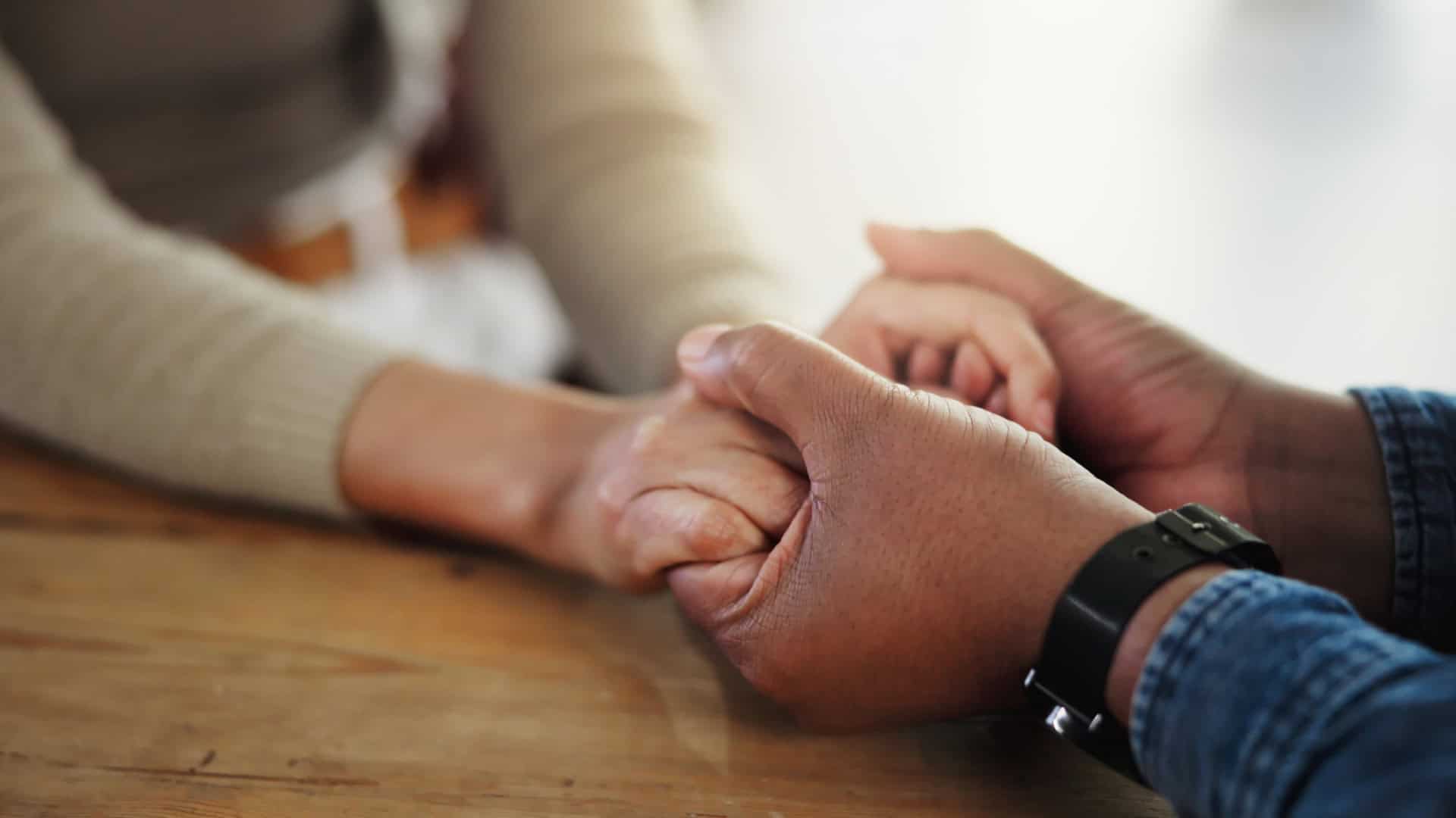 Pessoas de mãos dadas em cima da mesa