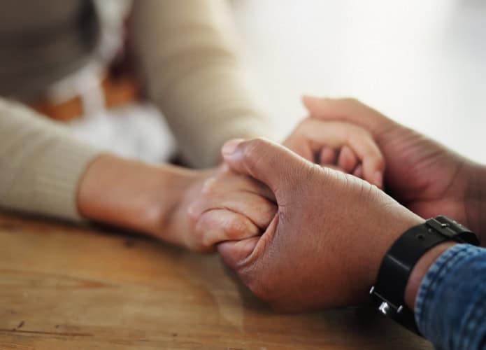 Pessoas de mãos dadas em cima da mesa