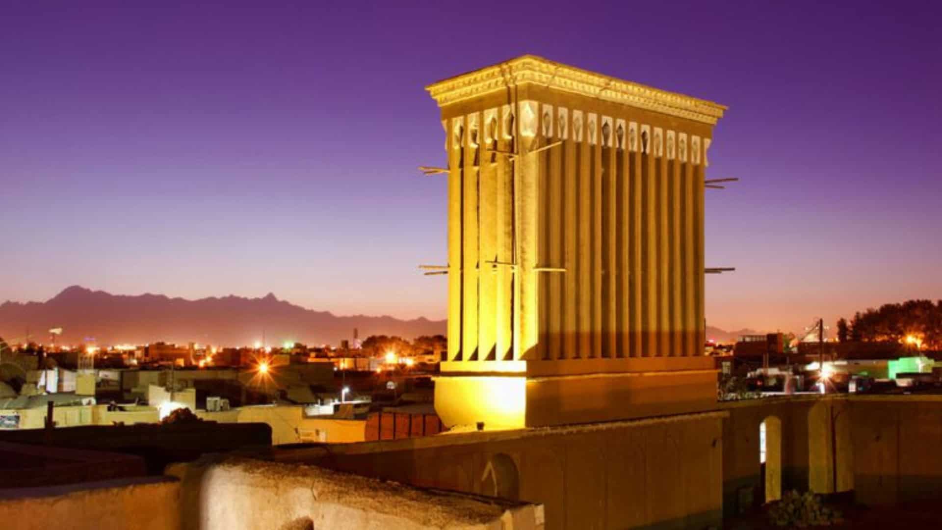 Construção amarela no meio de uma cidade mostrando as torres de vento