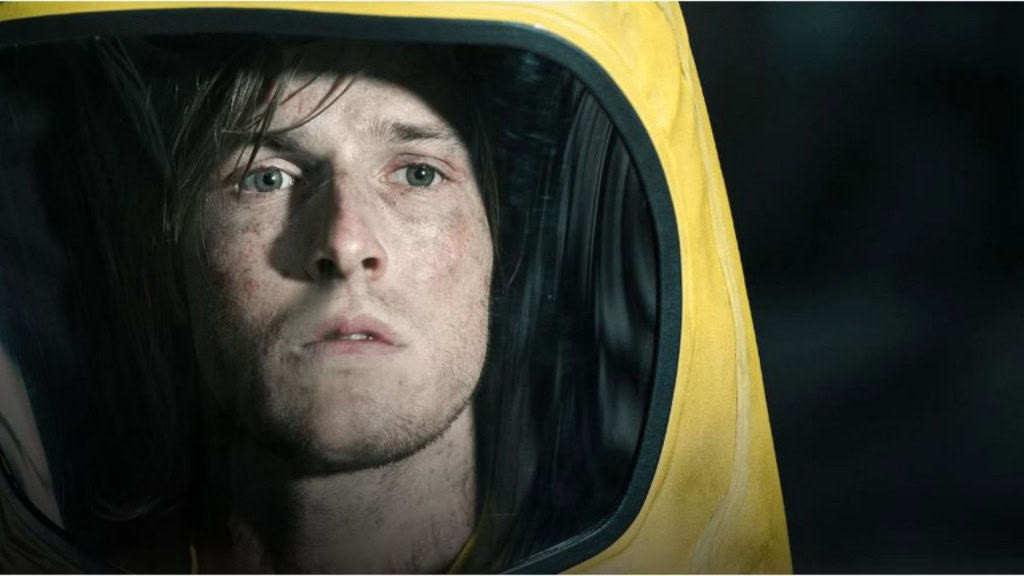 Imagem de um home com rosto sujo vestindo um macacão amarelo como se fosse de astronauta