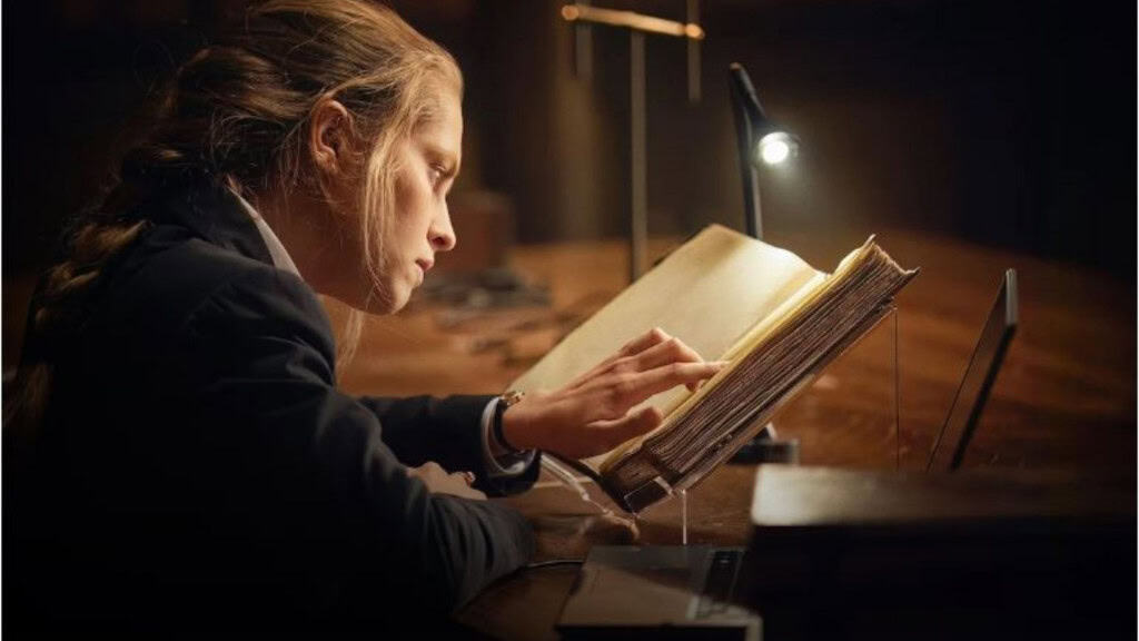 Imagem de jovem loira lendo livro sob a luz de uma luminária preta