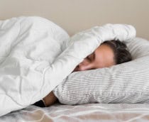 Mulher jovem da geração millennial dormindo coberta com cobertor. Inverno frio. Sem aquecimento em casa. Ronco alto. Sonhos doces. Ciclos circadianos.