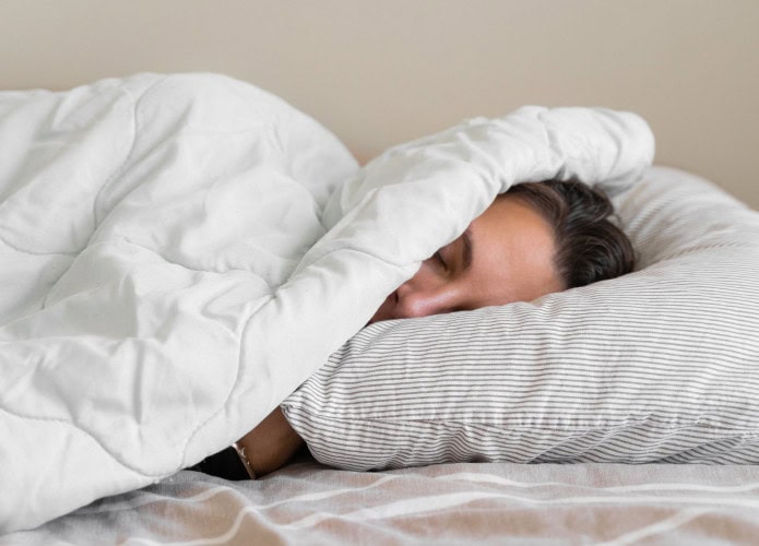 Mulher jovem da geração millennial dormindo coberta com cobertor. Inverno frio. Sem aquecimento em casa. Ronco alto. Sonhos doces. Ciclos circadianos.