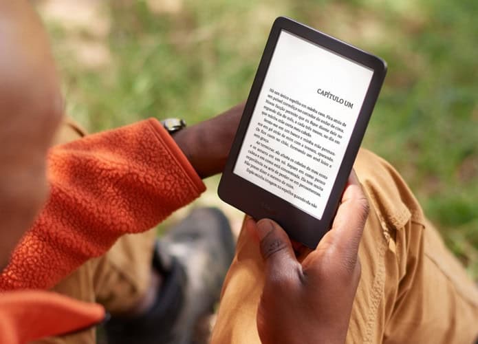 Homem lendo num Kindle num parque