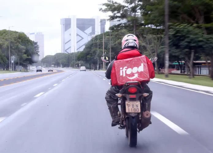 Motoboy com mochila do iFood andando em avenida de São Paulo