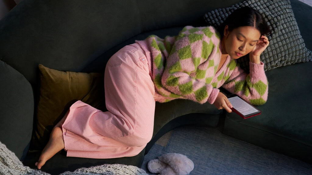 Mulher deitada de pijama lendo num Kindle