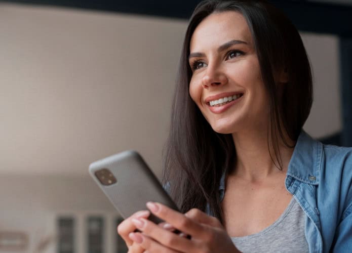 mulher sorri e olha enquanto segura celular