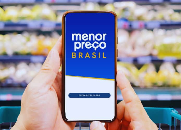 Mãos femininas usando celular no supermercado com o app Menor Preço Brasil