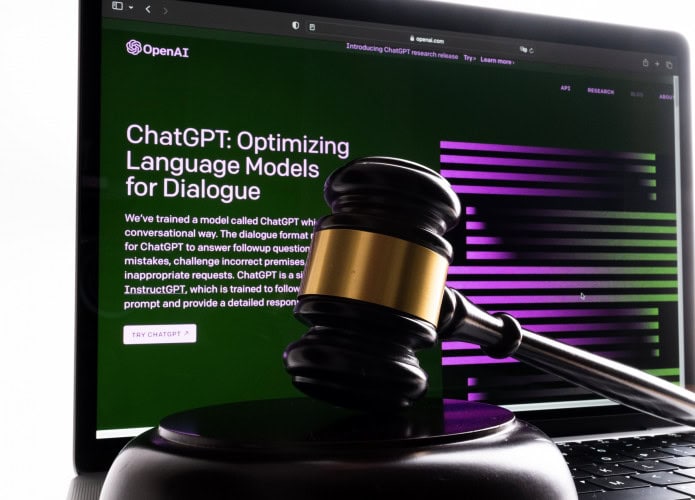 Ao fundo, site da OpenAI mostrando o ChatGPT; à frente, um martelo de juiz