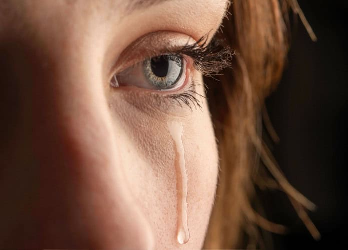 Close-up de uma jovem chorando com uma lágrima escorrendo pela bochecha