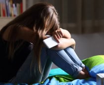 criança triste com um celular na mão