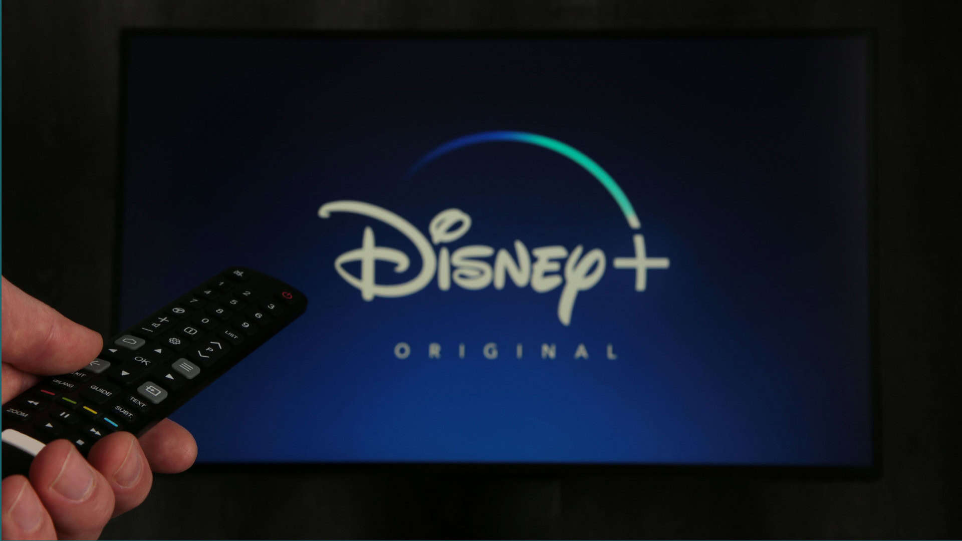 Tela de tv com o Disney+ aberto e uma pessoa com o controle remoto