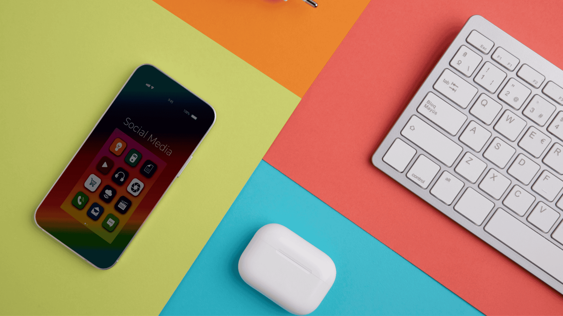 mesa com fundo colorido e um teclado, fone de ouvido e celular
