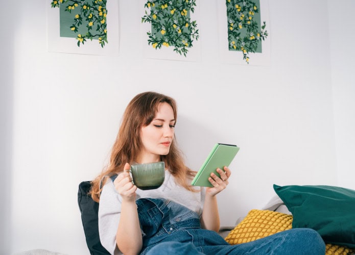 Mulher tomando chá e segurando um Kindle