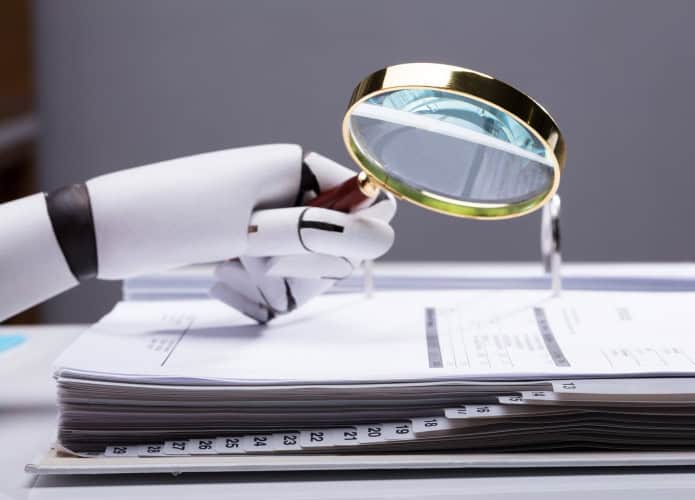 Mão de robô com uma lupa pairando sobre um caderno