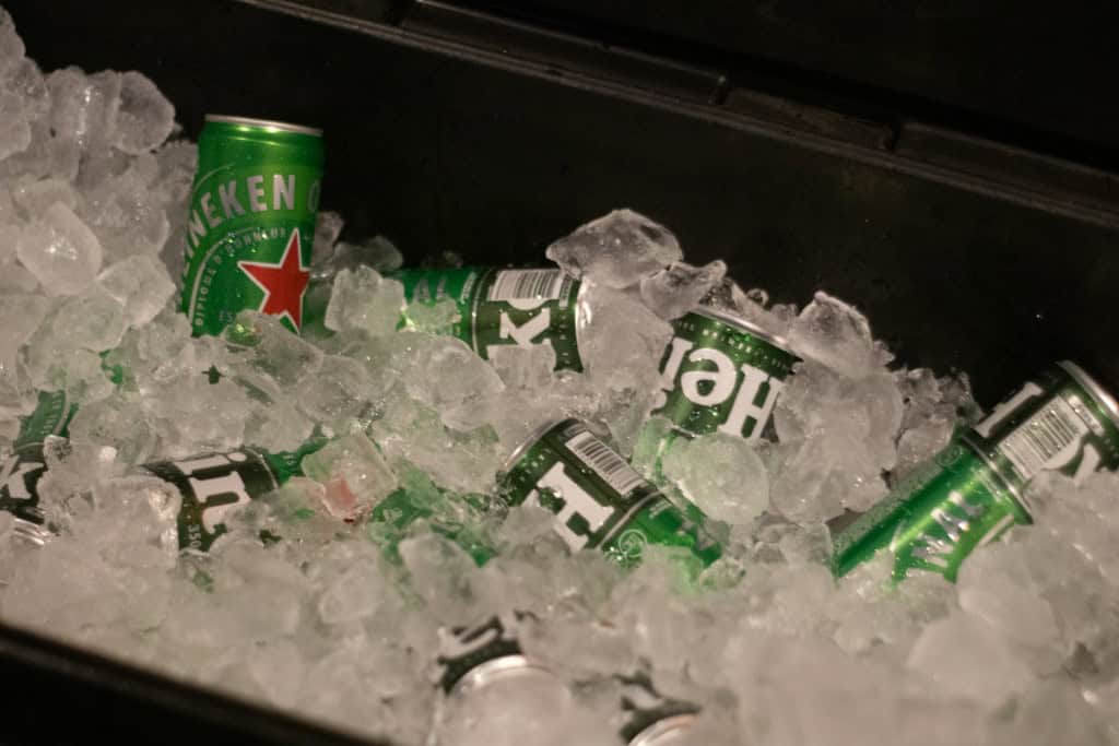 Latas de cerveja em um cooler com pedras de gelo