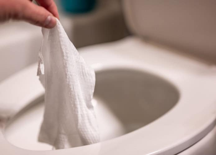 Pessoa descartando um lenço em um vaso sanitário