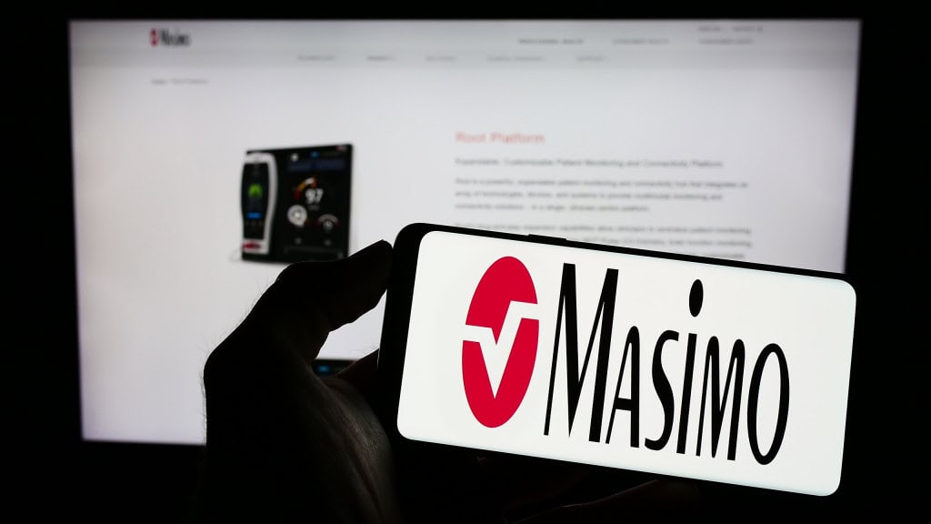 Ao fundo, site da Masimo; à frente, logo da empresa exibido em um smartphone