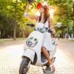 Mulher sorridente atraente andando de moto na rua com roupa estilo verão