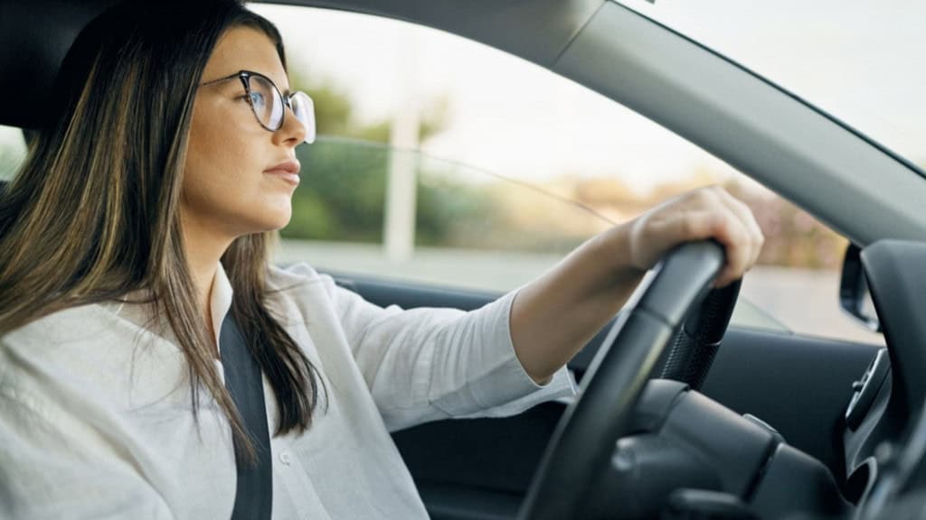 Mulher dirigindo um carro enquanto utiliza óculos de grau