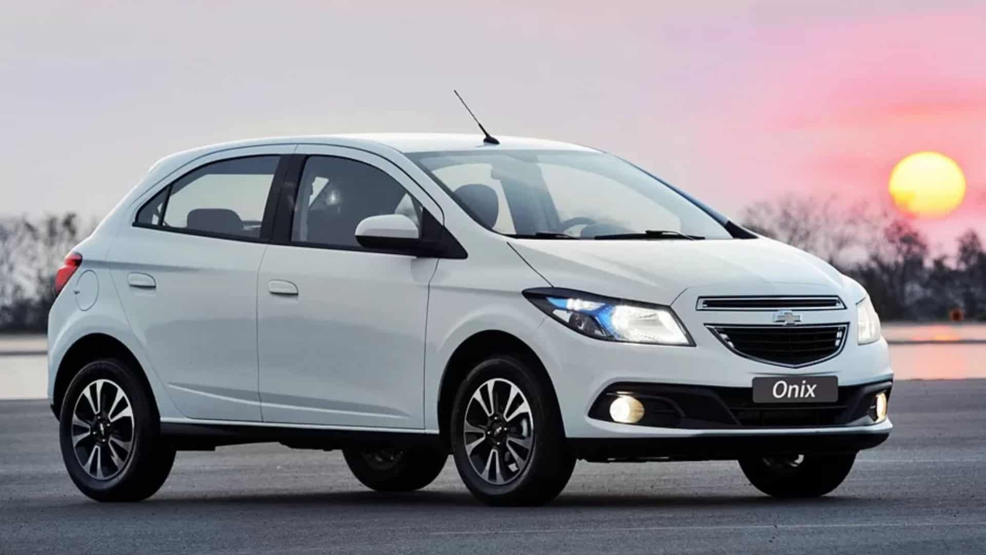 foto do carro Onix na versão branca com o por do sol atrás