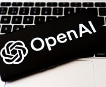 Logo da OpenAI em um smartphone que está em cima do teclado de um notebook