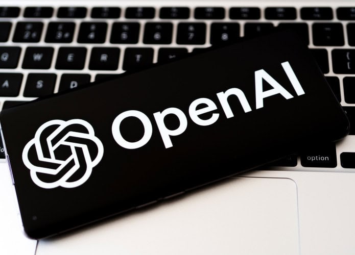 Logo da OpenAI em um smartphone que está em cima do teclado de um notebook