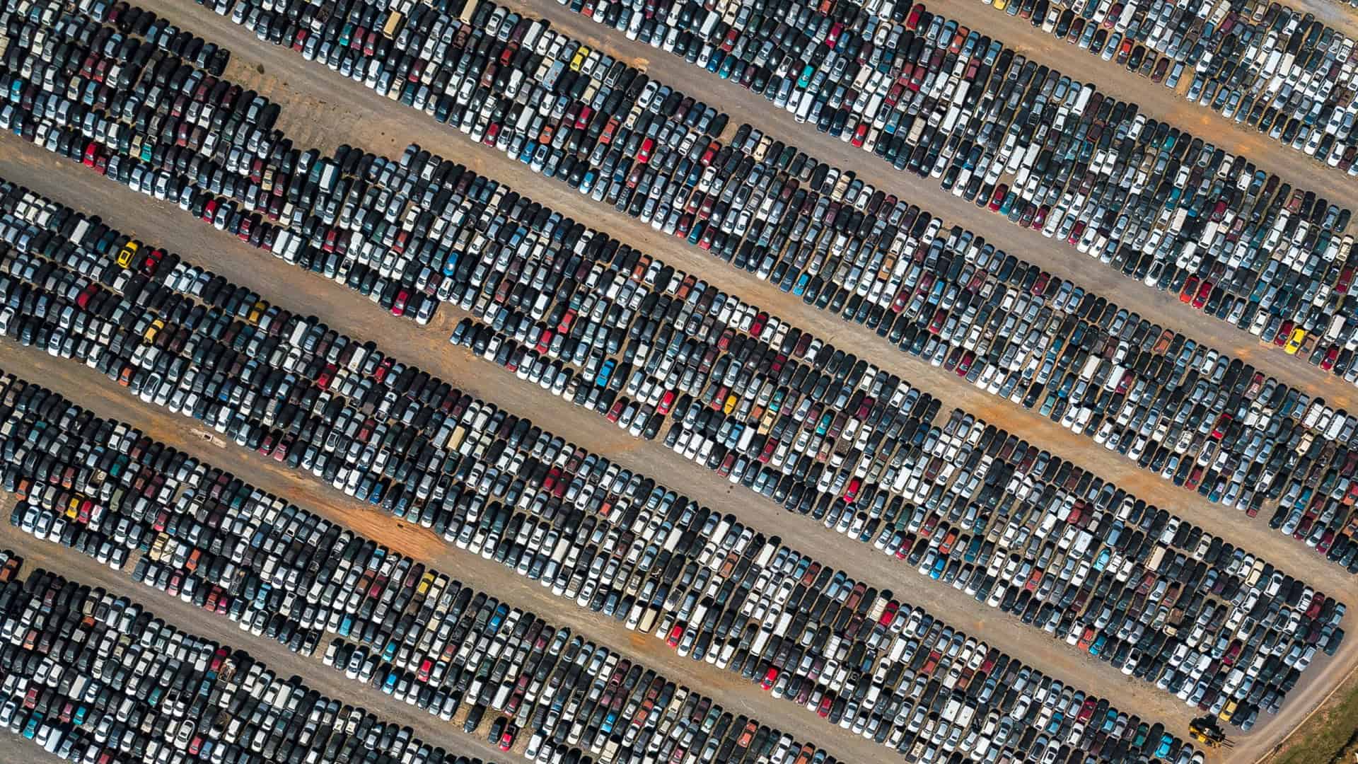 Pátio com centenas de carros estacionados visto de cima