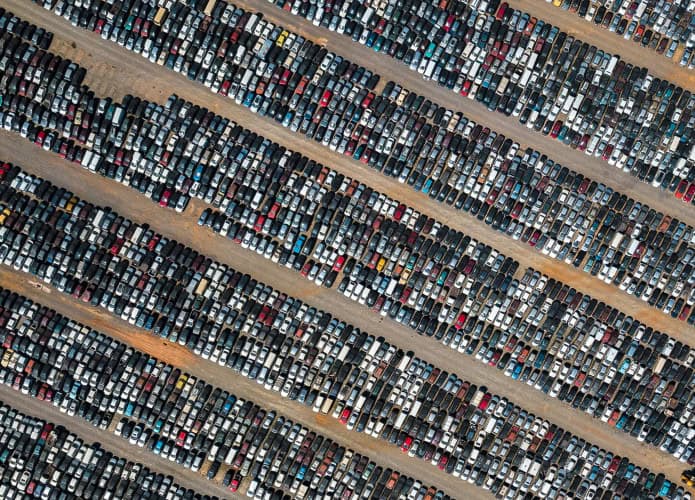 Pátio com centenas de carros estacionados visto de cima