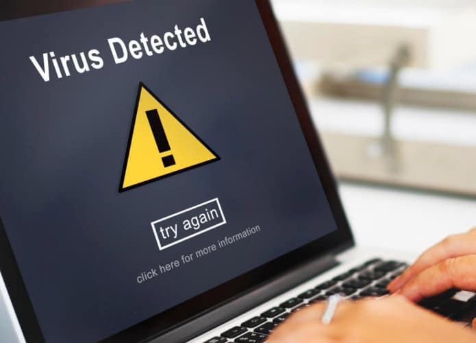 pessoa usando um laptop que tem uma mensagem de vírus na tela