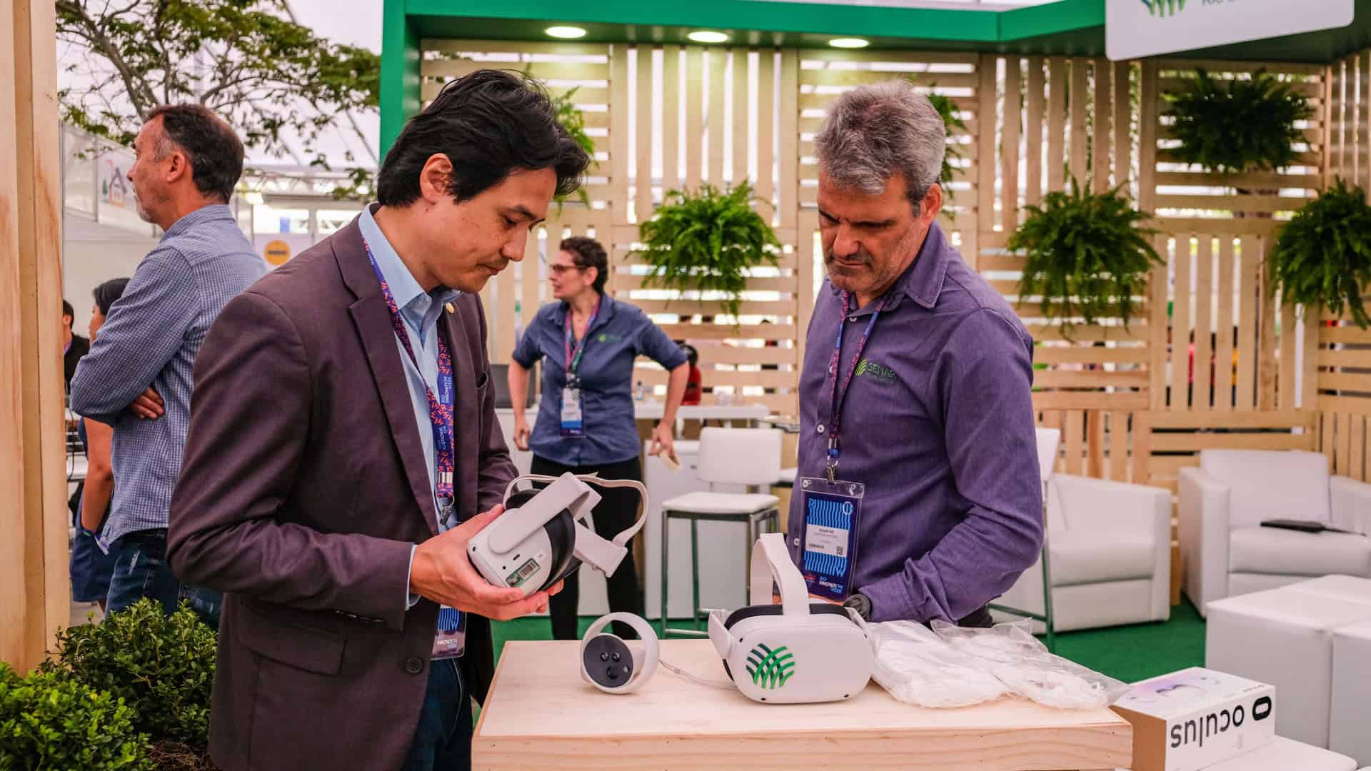 Dois homens olhando óculos de realidade virtual em cima de um balcão