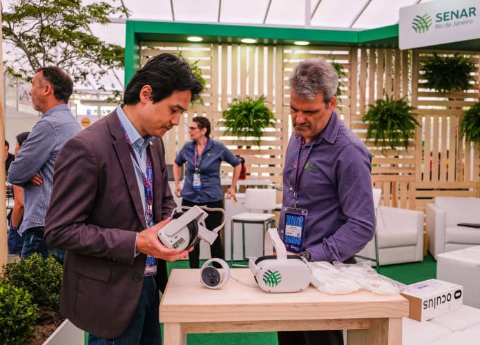 Dois homens olhando óculos de realidade virtual em cima de um balcão