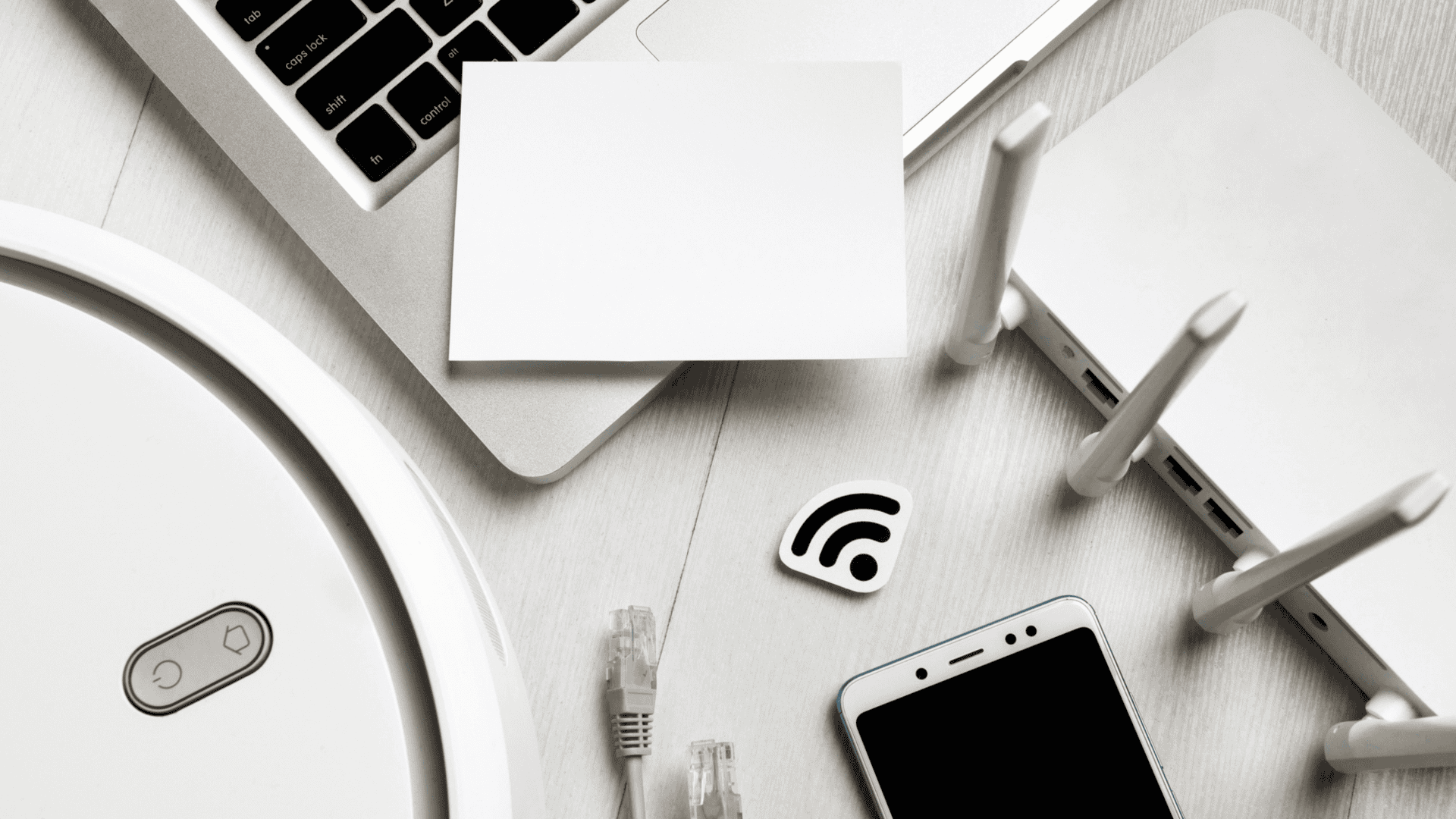 diversos dispositivos em cima da mesa, como laptop, celular e modem