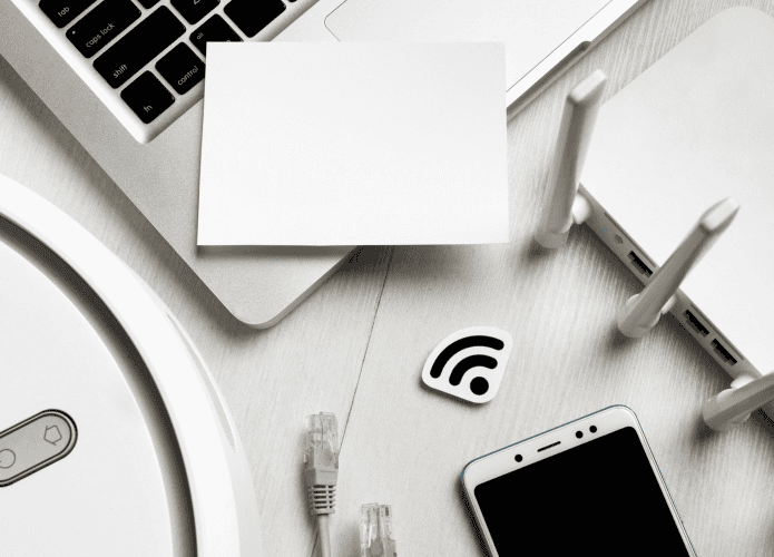 diversos dispositivos em cima da mesa, como laptop, celular e modem
