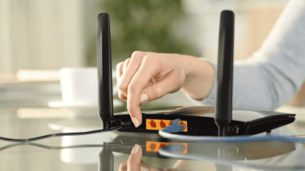 mão de uma mulher reiniciando o modem apertando o botão