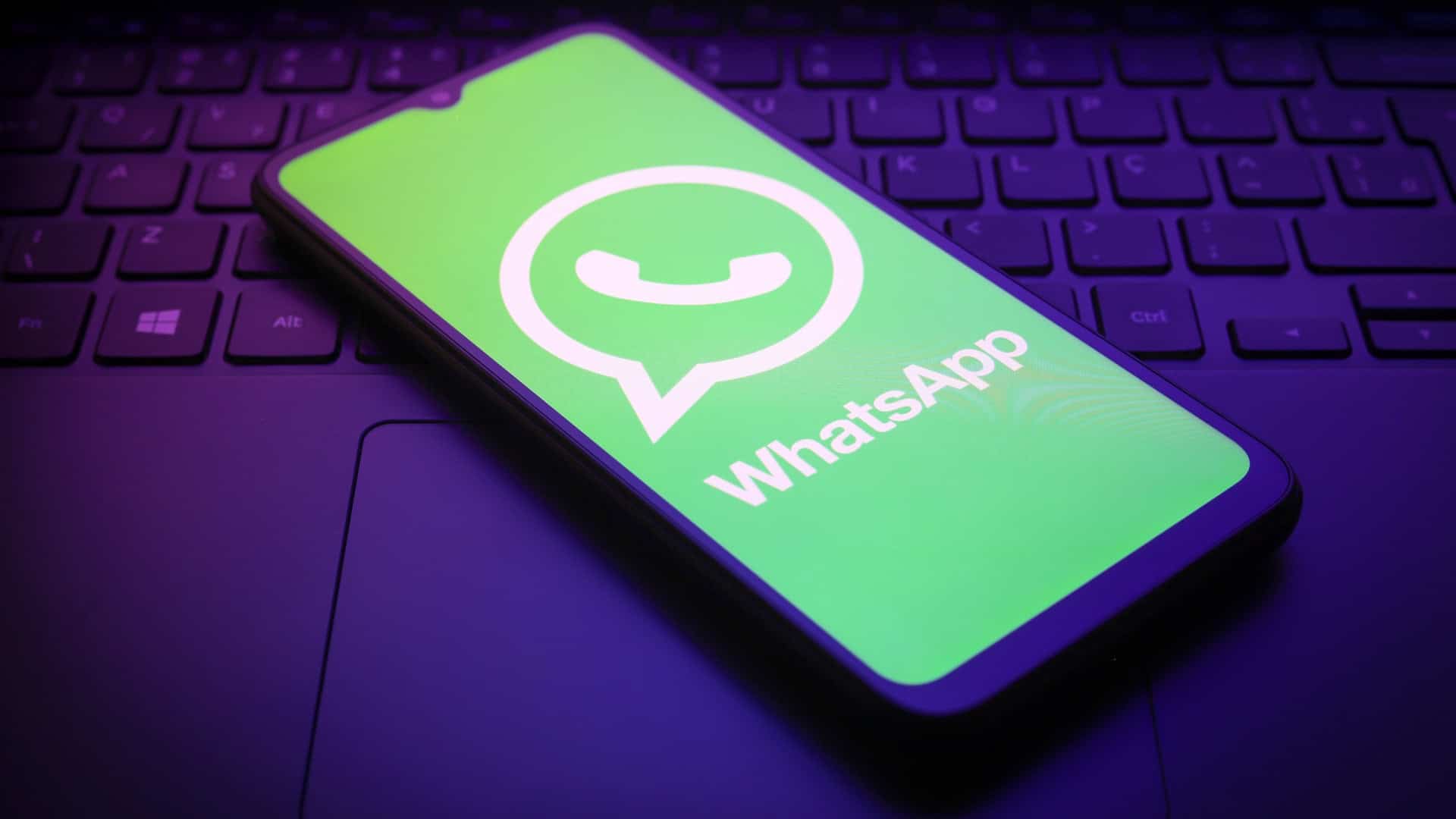 Logo do WhatsApp em um smartphone que está em cima de um teclado de notebook