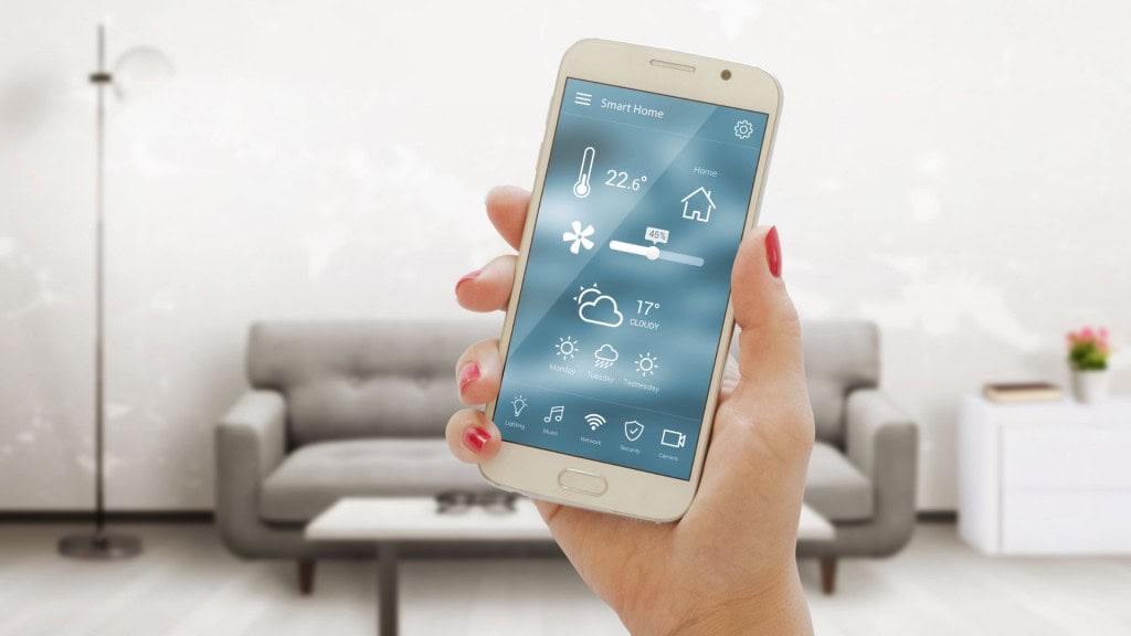 Mão mostrando celular com imagem de controle de temperatura corporal e ambiental