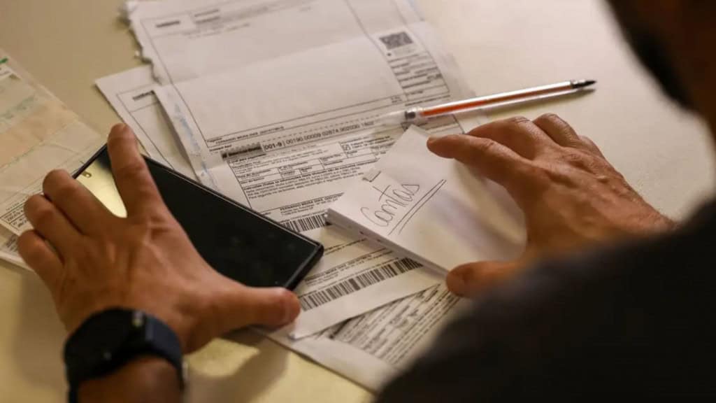 Homem lidando com contas usando calculadora e caneta