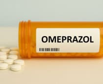 Caixa de comprimidos de omeprazol colocada sobre uma mesa, inibidor da bomba de protões para condições relacionadas com o ácido em uso diário.