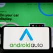 Estugarda, Alemanha - 14-03-2023: Pessoa segurando smartphone com o logotipo do aplicativo móvel Android Auto (Google) na tela em frente ao site. Foco na tela do telefone. Foto não modificada