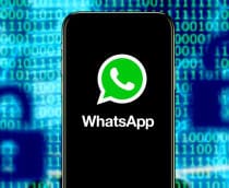 Celular com ícone do WhatsApp na tela na frente de tela mostrando códigos binários e desenhos de cadeados