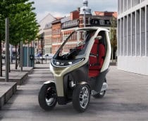 Montagem mostrando triciclo elétrico XYTE One na diagonal numa calçada na Europa