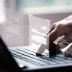 pessoa utilizando o computador com a montagem de arquivos sobre as mãos