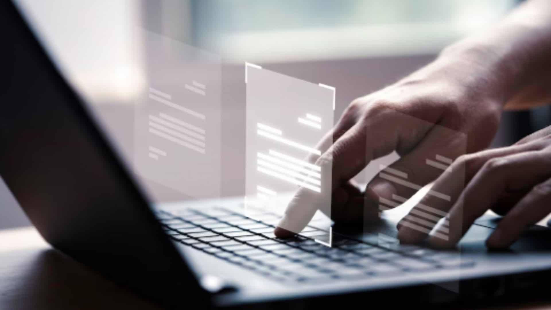 pessoa utilizando o computador com a montagem de arquivos sobre as mãos